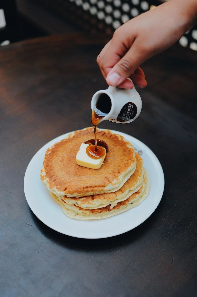 syrup being poured on pancakes