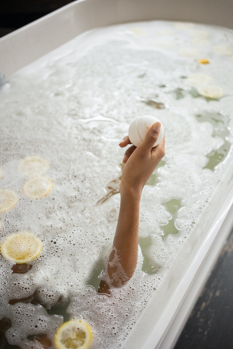 woman holding bath bomb while being in the bath