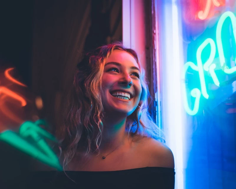 woman laughing in front of neon sign