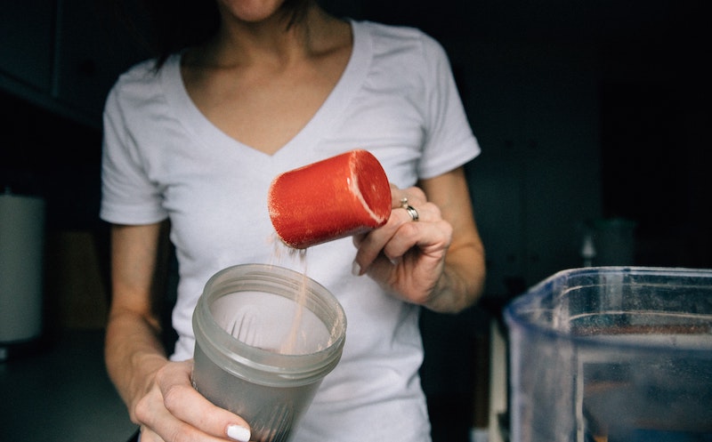 woman putting protein scoop in shake