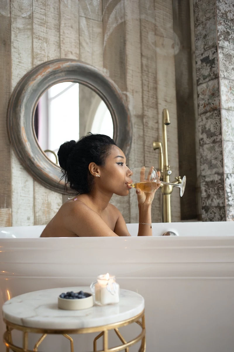 woman sitting in the bathtub drinking a glass of wine