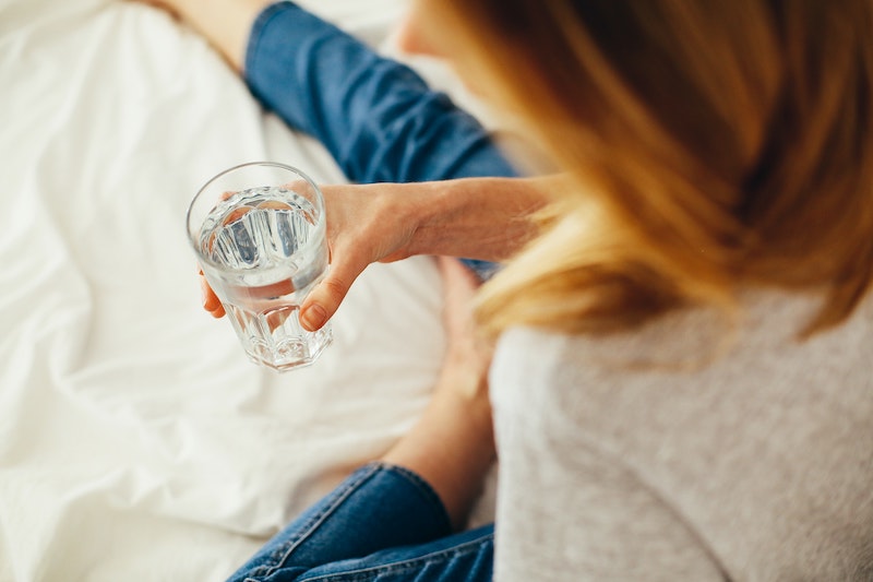 woman sitting on the bed with a glass of water