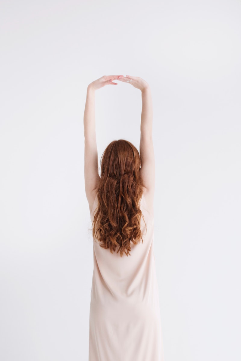 woman with red hair and arms up on white background