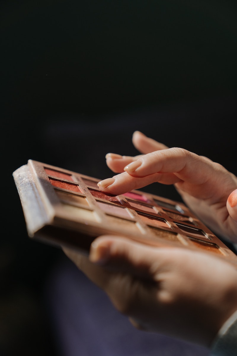 fingers touching a makeup pallete of eye shadow