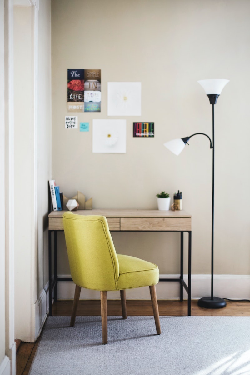 green chair in front of desk with floor lamp