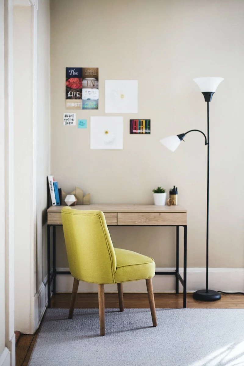 green chair in front of desk with floor lamp