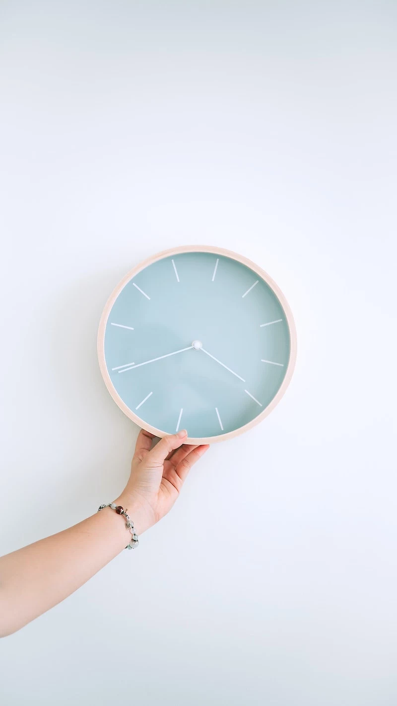 hand holding a wall clock in blue