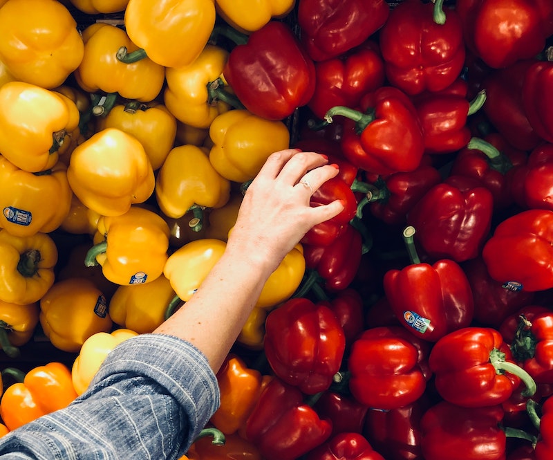 hand picking in between red and yellow peppers