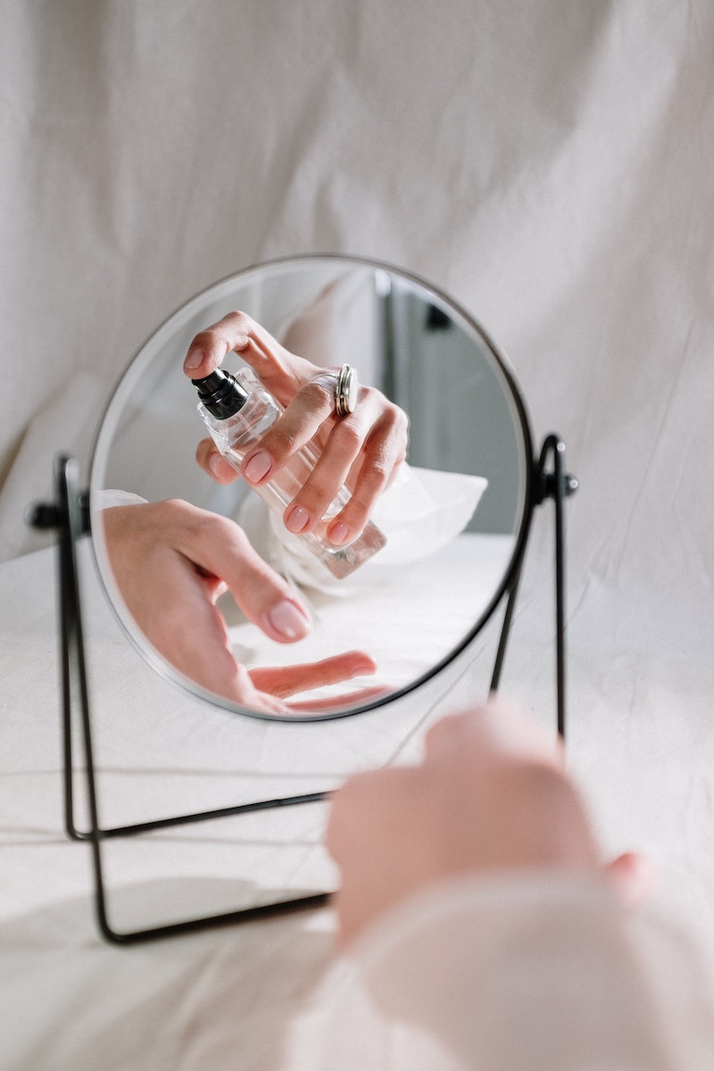 hand sprayin perfume in front of mirror