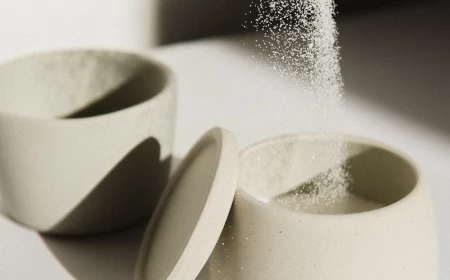 high in sugar sugar being poured from spoon to container
