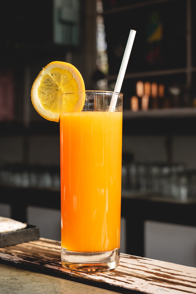 ornage juice in a tall glass with a straw