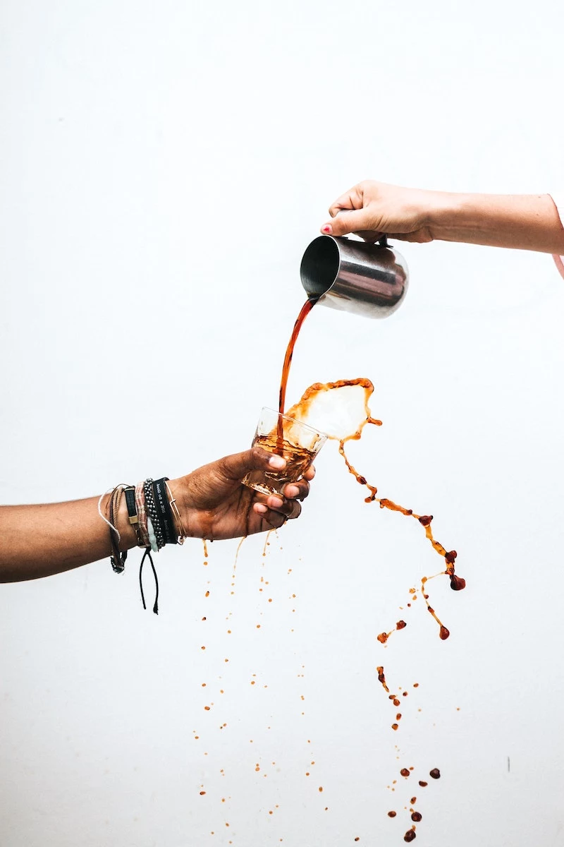 people pouring coffee into a cup and it spilling