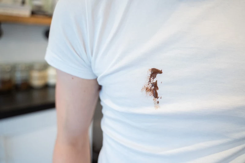 person wearing a white t shirt that is stained with chocolate