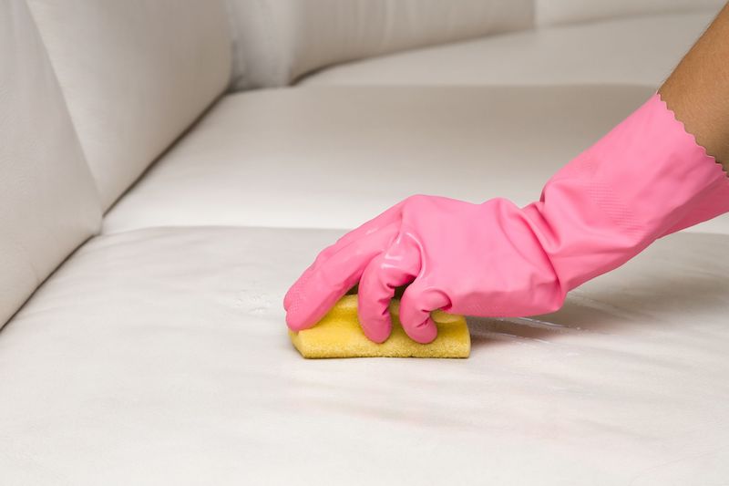 person with pink gloves rubbing at a stain