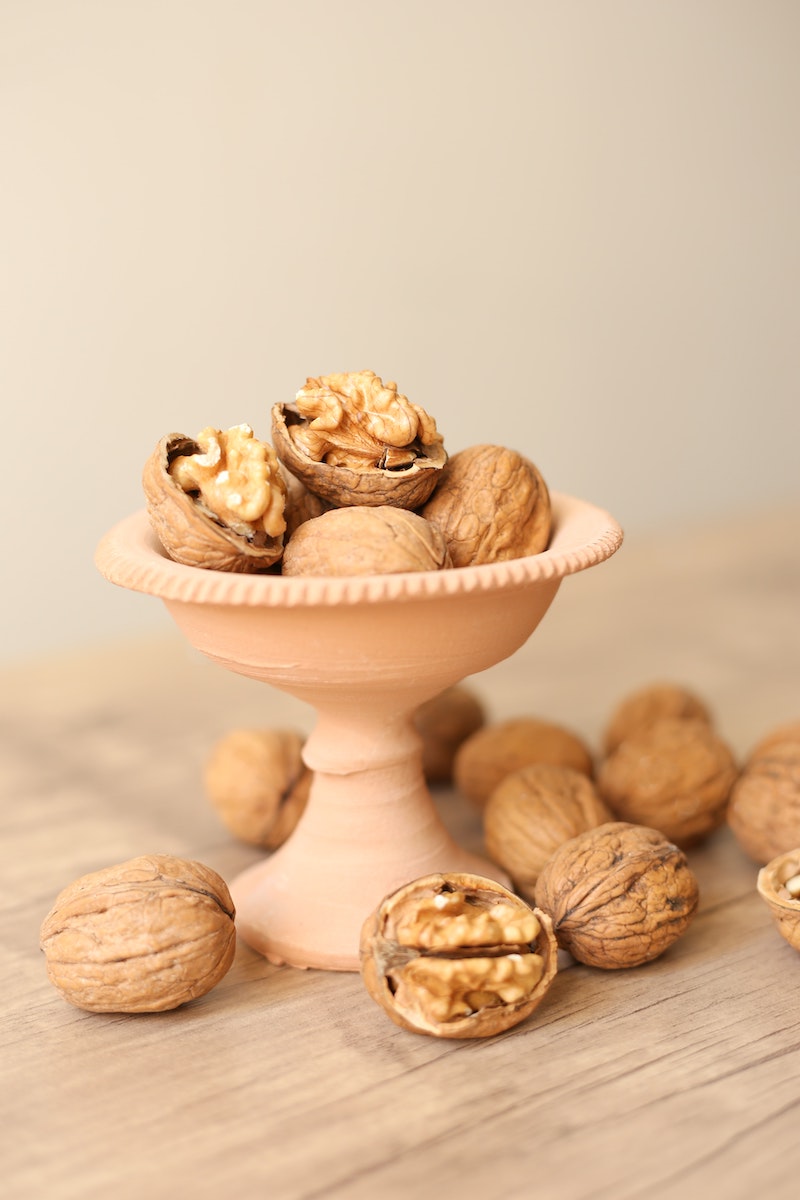 whole and broken walnuts in a pink bowl
