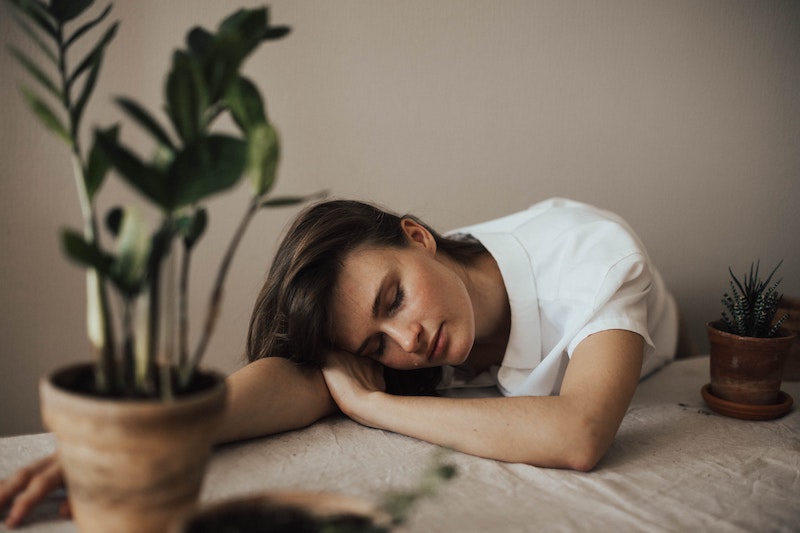 woman fallen asleep on table with plant