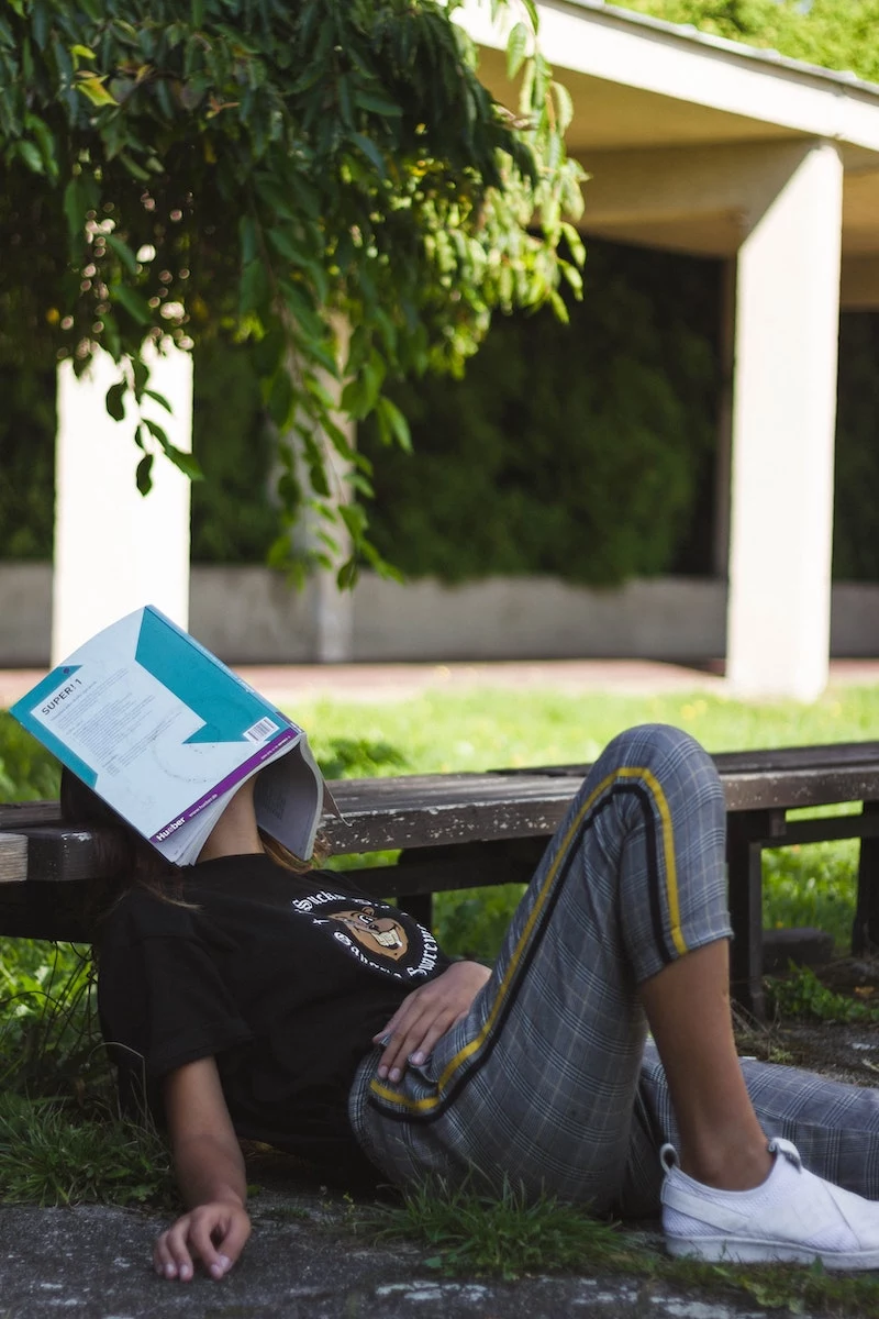 woman fallen asleep under text book outside