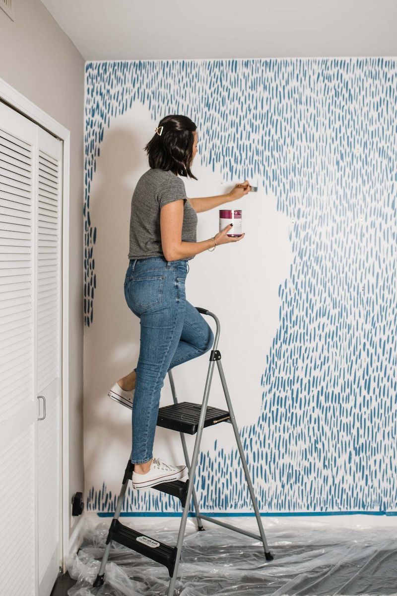 woman paining wall in strokes