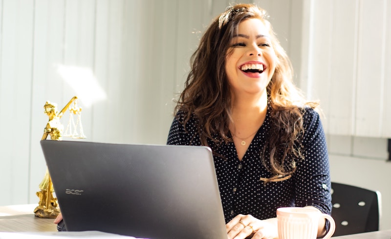 woman sitting in front of laptop laughing