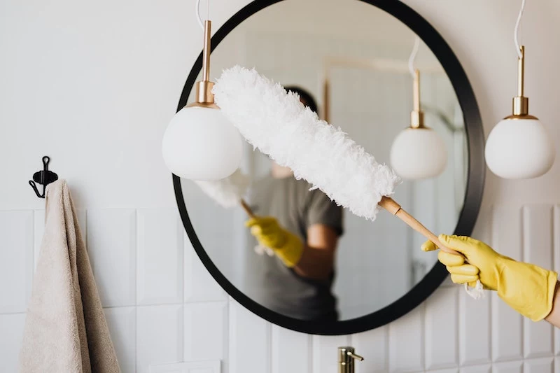 woman sleaning with a feather duster a mirror
