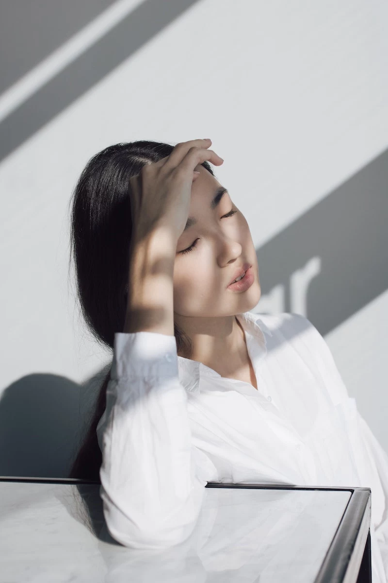 asian woman protecting her eyes from the sun with hand