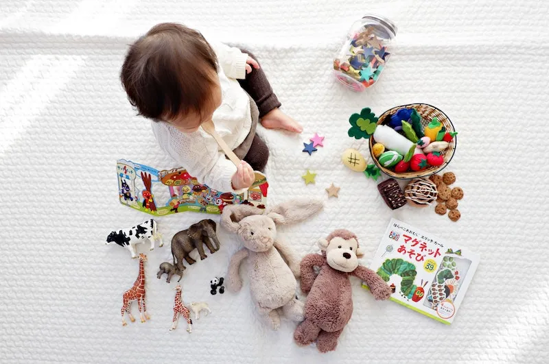 baby surrounded by different toys