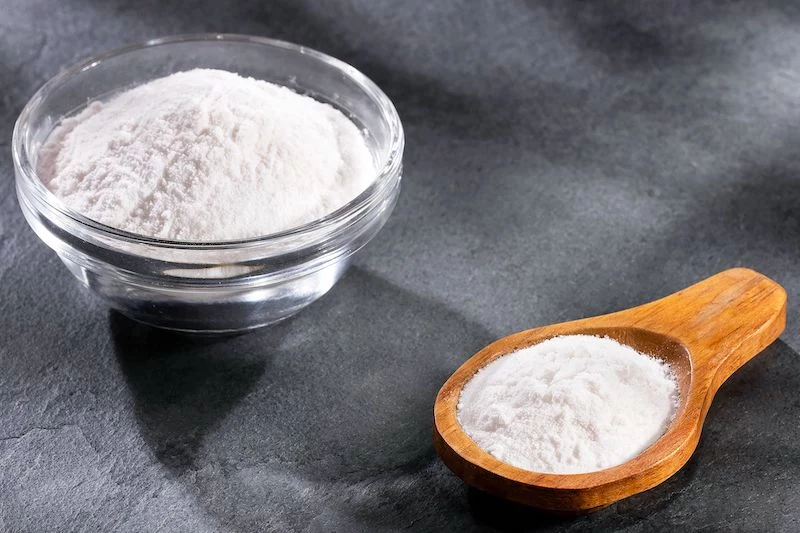 baking soda in a glass bowl and wooden spoon