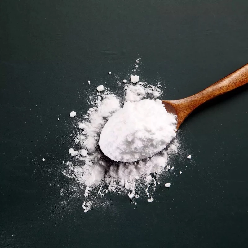 baking soda in wooden spoon spilt on black background