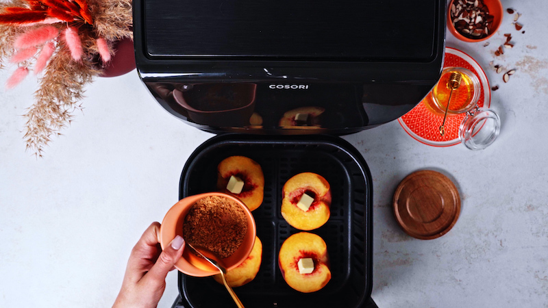 batch bowl held above air fryer with peaches