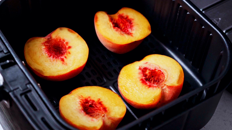 batch four peach halves in an air fryer basket