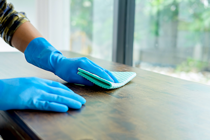 blue gloves cleaning a table