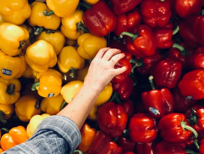 foods you should eat raw hand picking out peppers from store