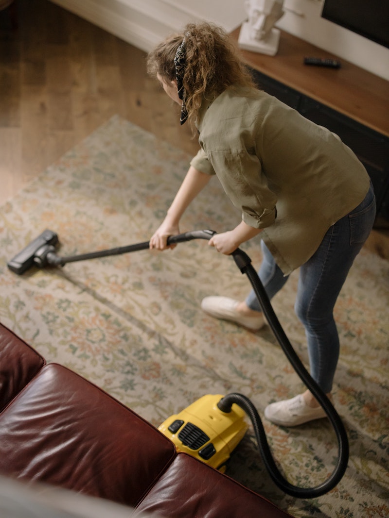 get rid of fleas in the house woman vacuuming her carpet