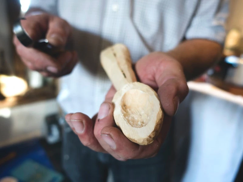 man with carved out spoon of wood