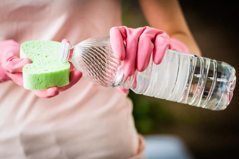 woman using white vinegar to clean