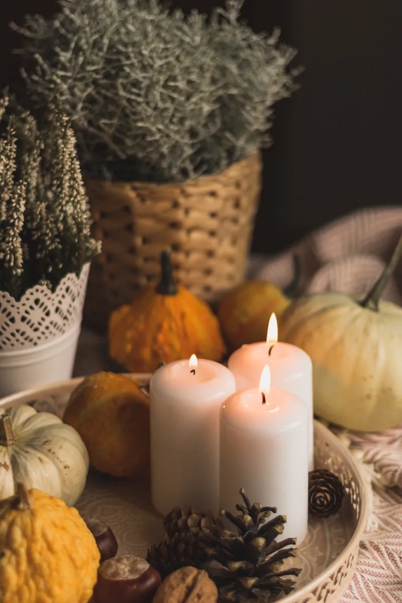 three lit candles with pumpkins