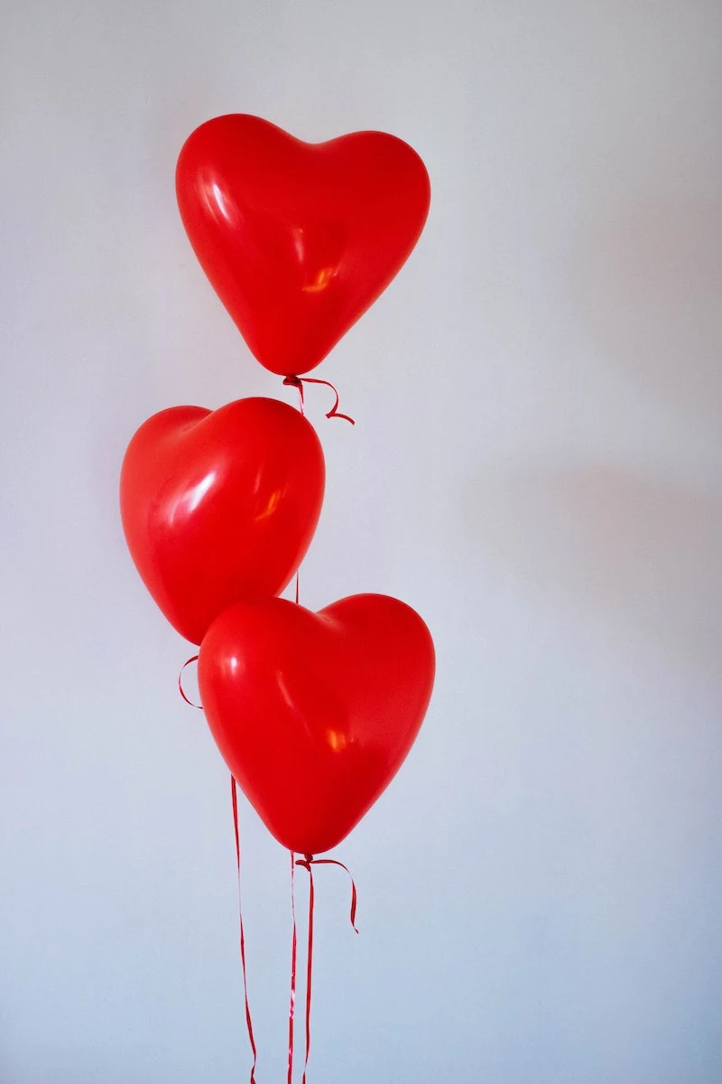 three red heart baloons floating