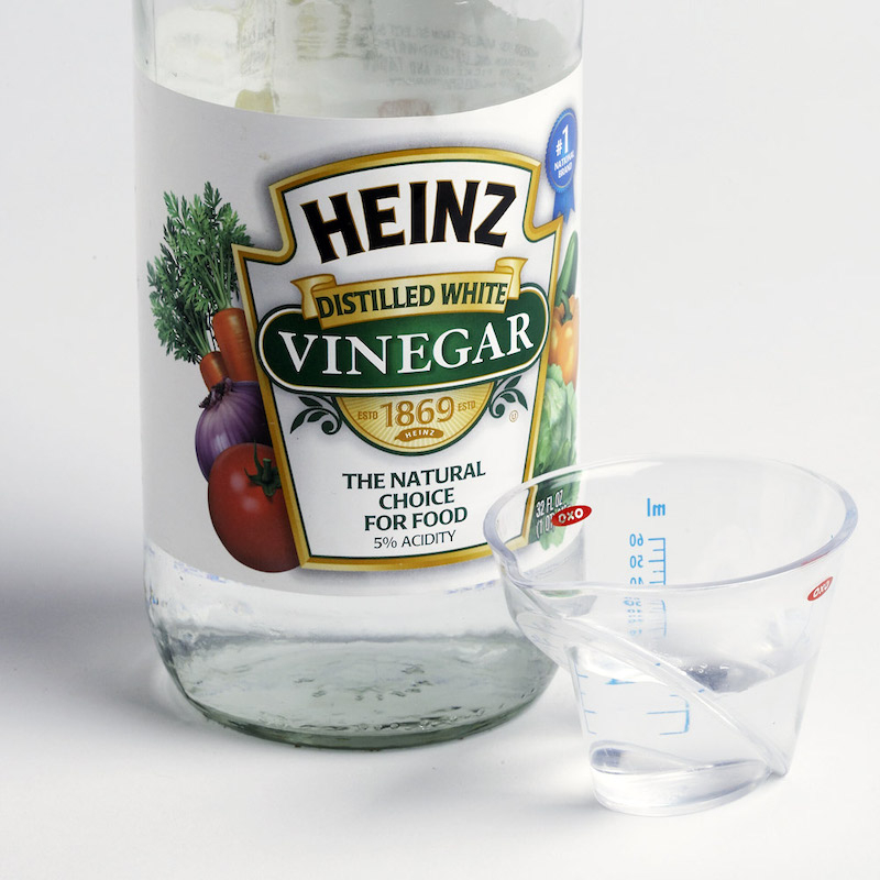 white distilled vinegar in a bottle and in a cuo