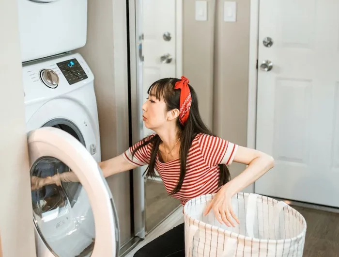 woman with a hamper placing clothes in the washing machine