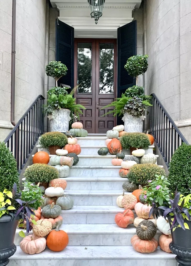 black door with pumpkins down the stairs