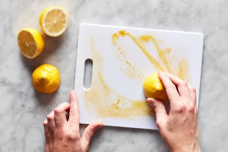 cleaning a plastic cutting board with a lemon