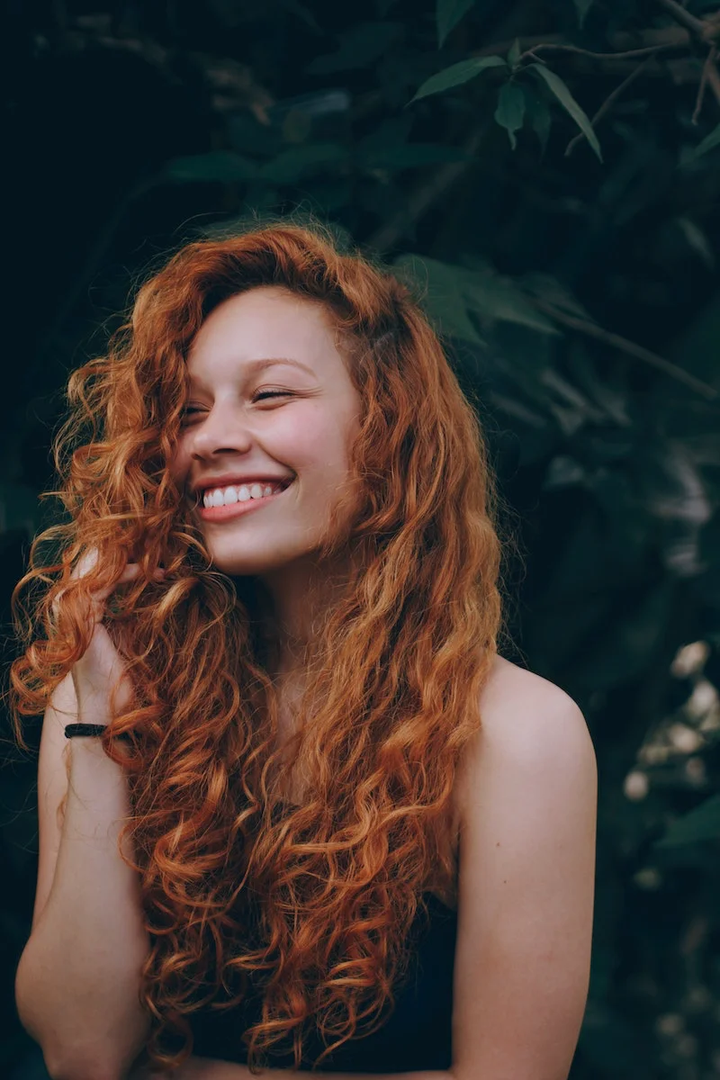 habits that are damaging your hair red head woman holding her curly hair