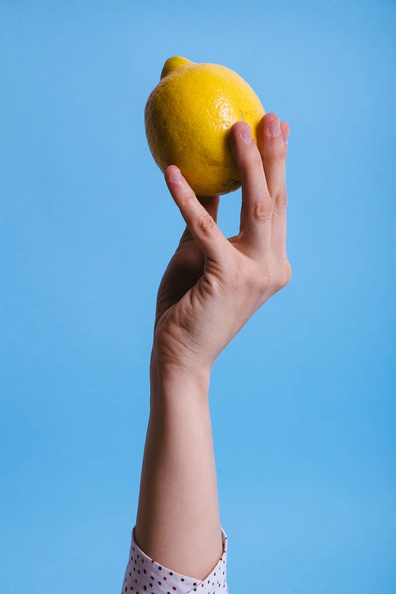 hand on blue background holding a lemon