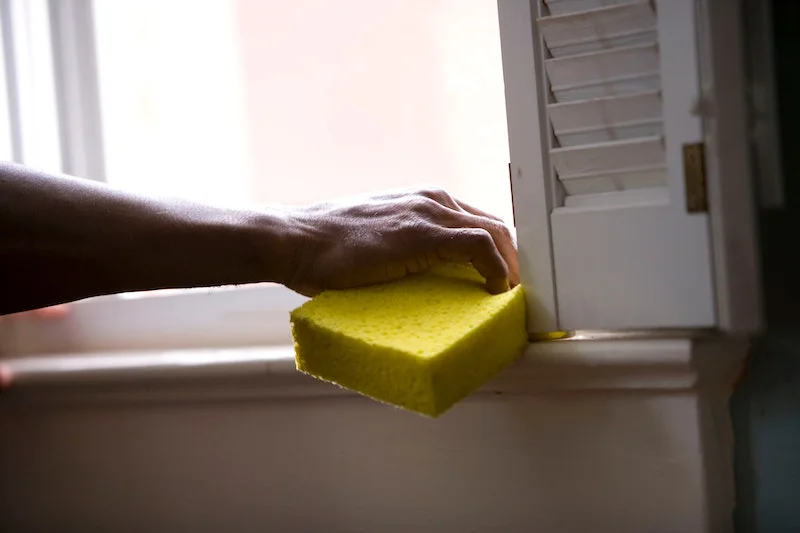 how to clean construction dust hand cleaning windowsill with yellow sponge
