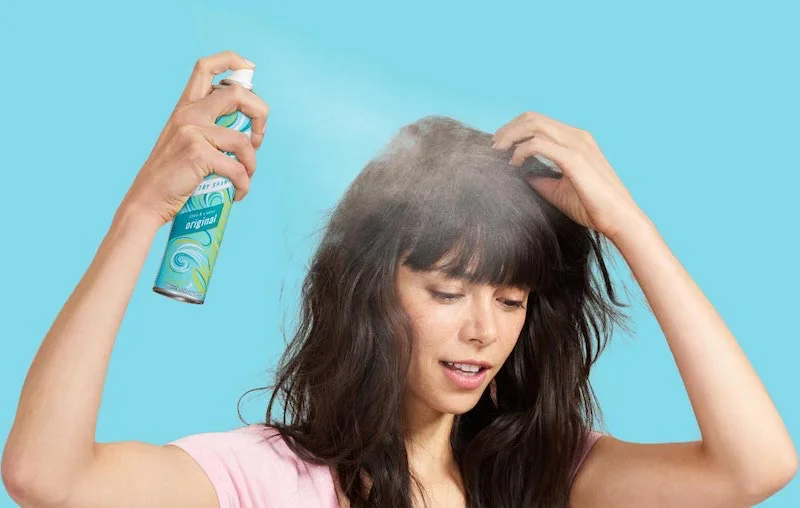 how to use dry shampoo woman spraying in dry shampoo