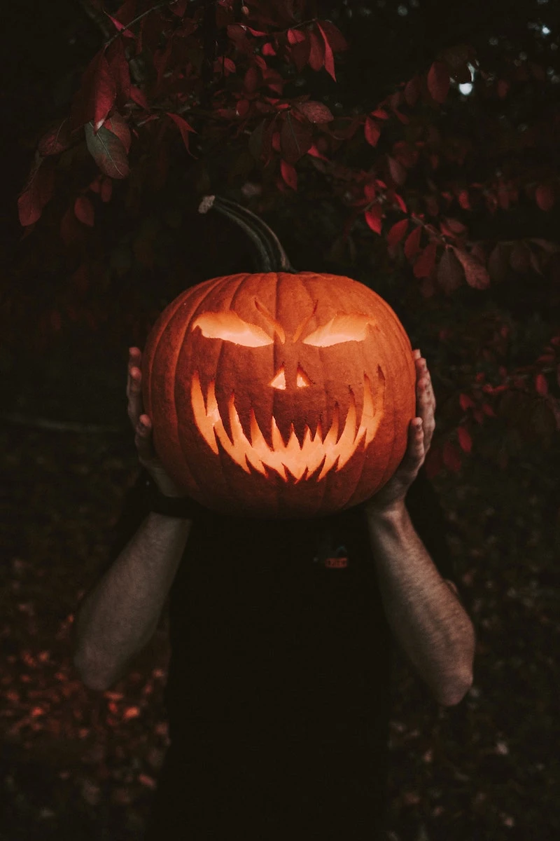 man holding scary carved pumpkin