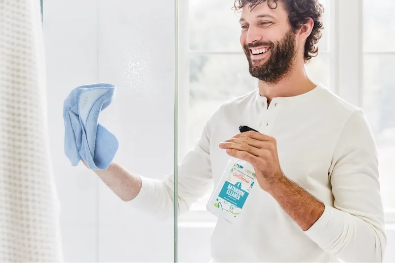 man smiling while cleaning bathroom