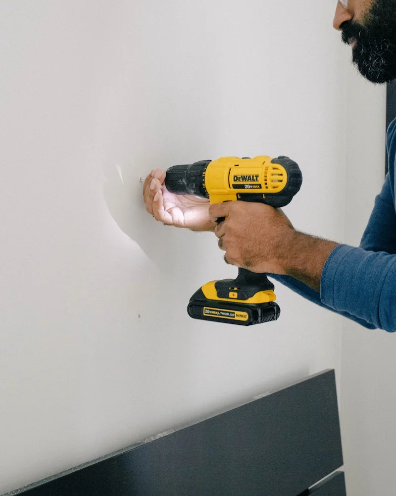 man using a yellow and black drill in wall