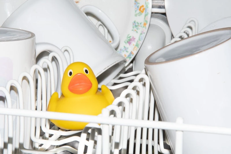 overcrowded dishwasher with a rubber duck inside