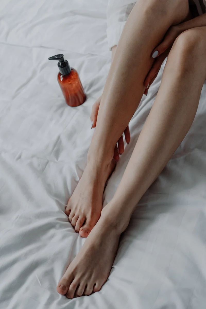 person applying lotion to their legs